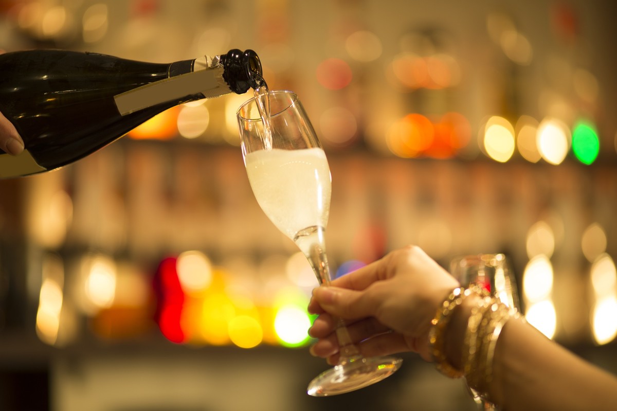 Women ask pouring champagne into a glass