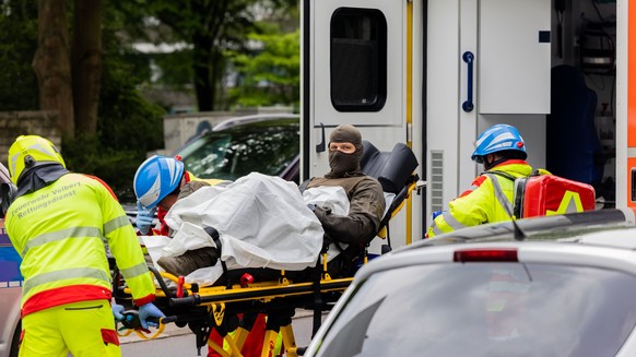 11.05.2023, Nordrhein-Westfalen, Ratingen: Ein verletzter Polizeibeamter wird vor einem Hochhaus in einen Krankenwagen gebracht. Bei einer Explosion in einem Hochhaus in Ratingen am Donnerstagvormitta ...