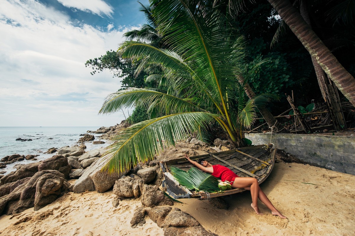 Beautiful girl on a Paradise beach. Girl sunbathing on the beach. Beautiful woman on the beach. A girl on a beautiful island. The girl on the Islands. Sea. Beach. Sand. Boat. Model in swimsuit.