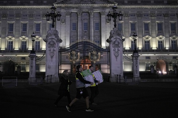 02.05.2023, Großbritannien, London: Arbeiter tragen Pizzakartons an den Toren des Buckingham Palace vorbei. Wenige Tage vor der Krönung von König Charles III. (74) ist es am Buckingham-Palast zu einer ...