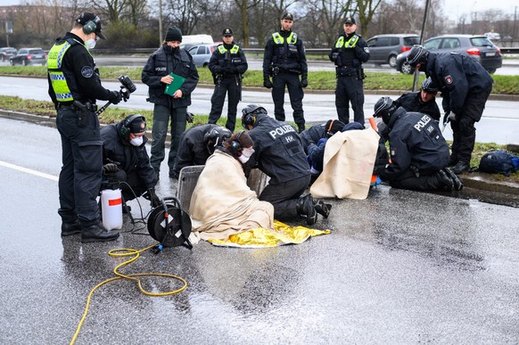 25.03.2023, Hamburg: Polizisten arbeiten an den festgeklebten Aktivisten. Klimaaktivisten der Bewegung �Letzte Generation� haben am Samstag die Elbbr�cken stadteinw�rts blockiert. Vier Personen haben  ...