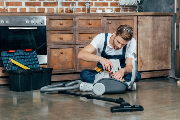 professional repairman fixing vacuum cleaner