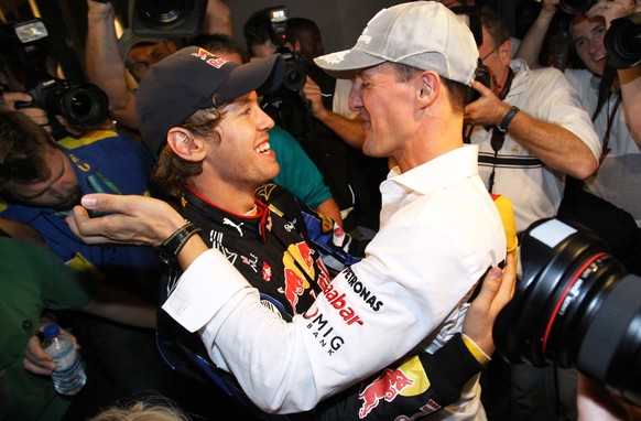 ARCHIV - 14.11.2010, Vereinigte Arabische Emirate, Abu Dhabi: Der deutsche Formel-1-Rennfahrer Sebastian Vettel (l) vom Team Red Bull wird nach seinem WM-Sieg von Michael Schumacher (Mercedes GP) begl ...