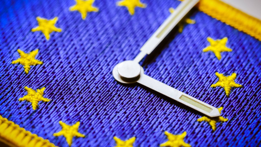 Uhrzeiger auf EU-Fahne, Abschaffung der Zeitumstellung *** Clock hand on EU flag. Abolition of the time change