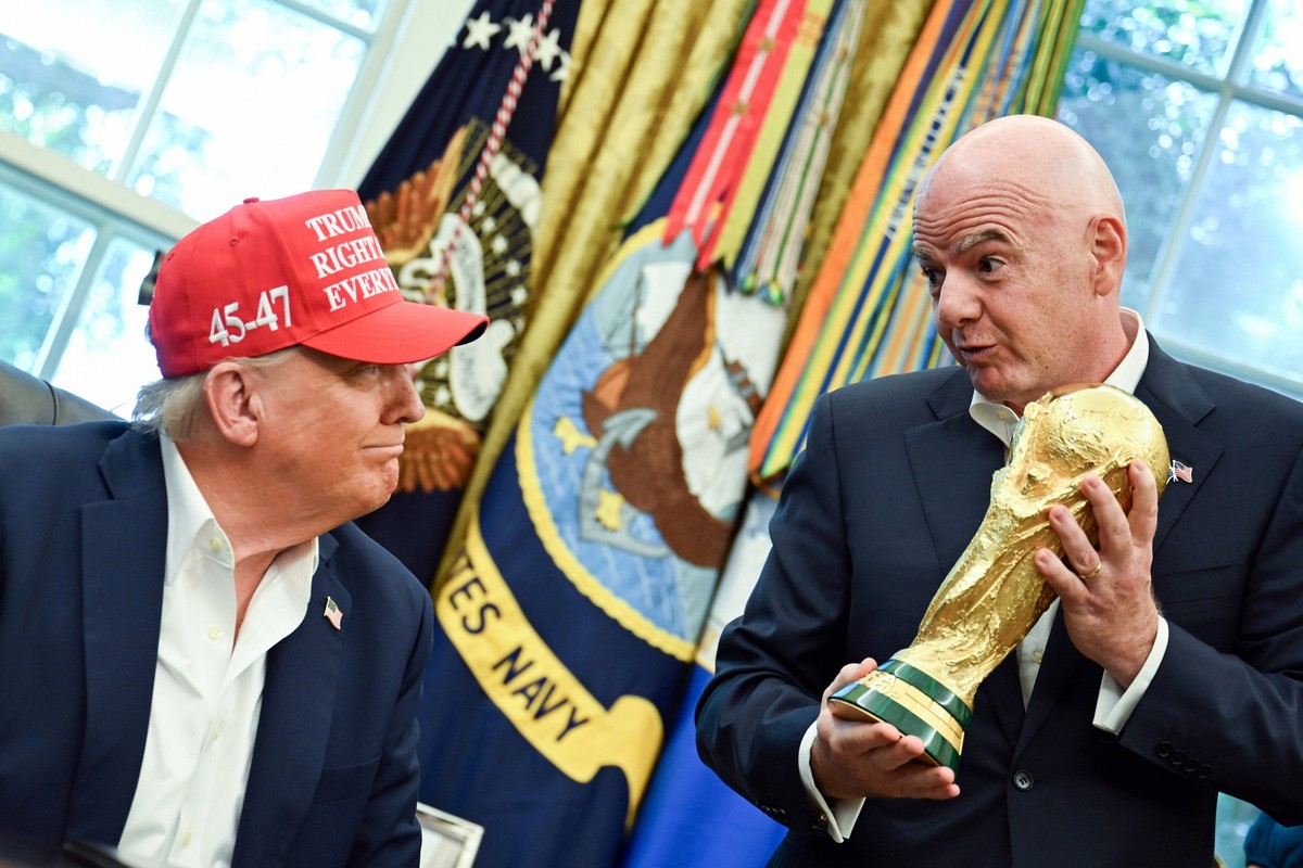 FIFA President Gianni Infantino hands President Donald Trump the FIFA World Cup trophy after announcing the 2026 World Cup draw will be held at the Kennedy Center in December in the Oval Office of the ...