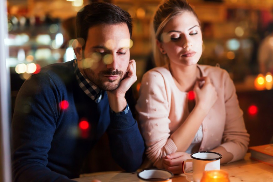 Sad couple having conflict and relationship problems sitting in bar