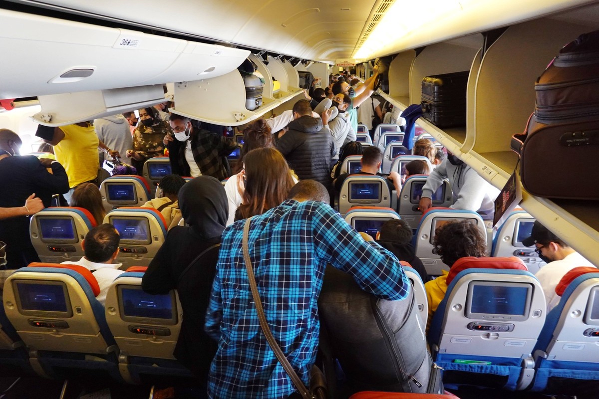 27.03.2022, Istanbul, TUR - Menschen holen in einer Flugzeugkabine der Turkish Airlines nach der Landung das Handgepaeck aus den Gepaeckfaechern. Airline, Alltag, asiatisch, Asien, Ausstieg, Bildschir ...
