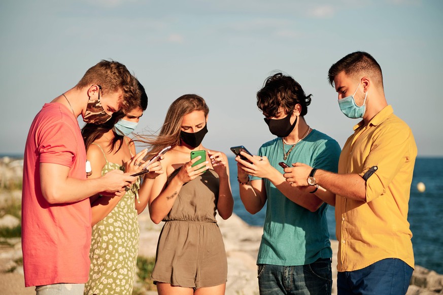 a group of young people wearing face mask and mobile phones in a summer day Barcelona, CT, Spain PUBLICATIONxINxGERxSUIxAUTxONLY CR_EYEM200803B-460852-01 ,model released, Symbolfoto ,property released