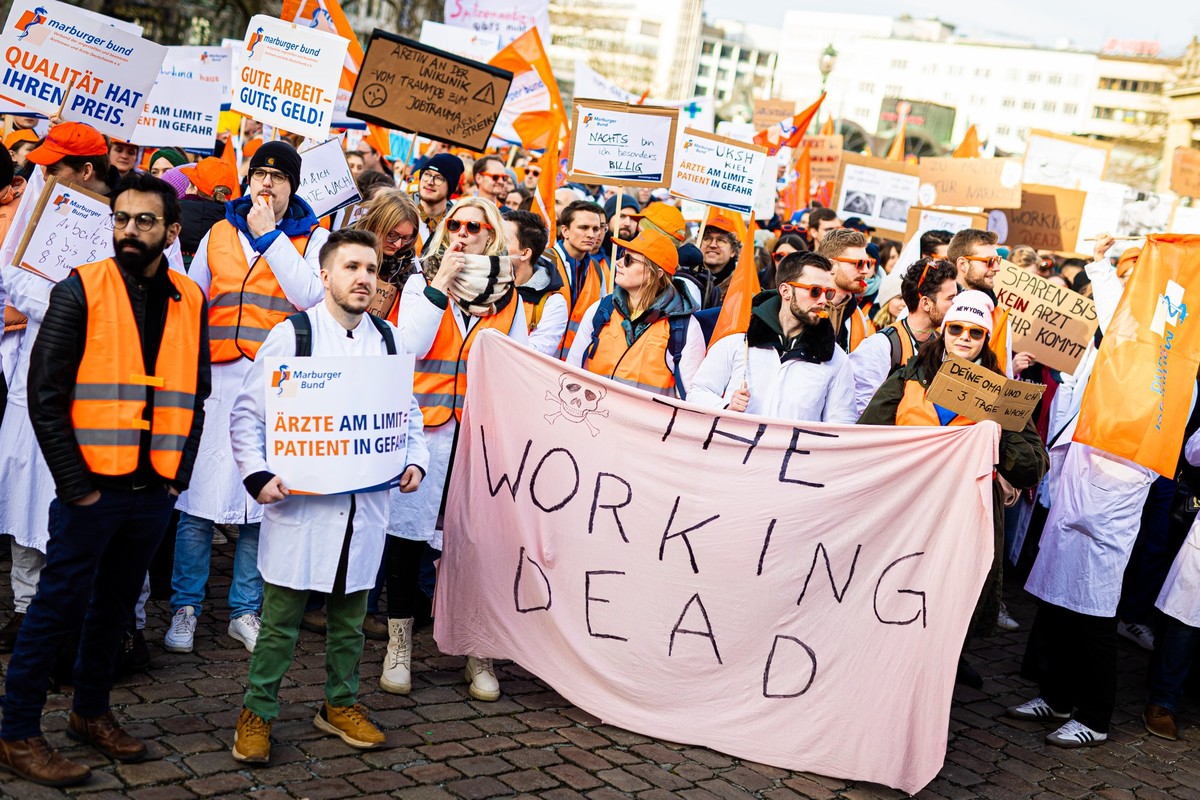 30.01.2024, Niedersachsen, Hannover: Menschen nehmen an einer Demonstration von Uniklinik-�rzten auf dem Opernplatz teil. Auf einem Transparent steht �The Working Dead�. Im Tarifstreit mit den L�ndern ...