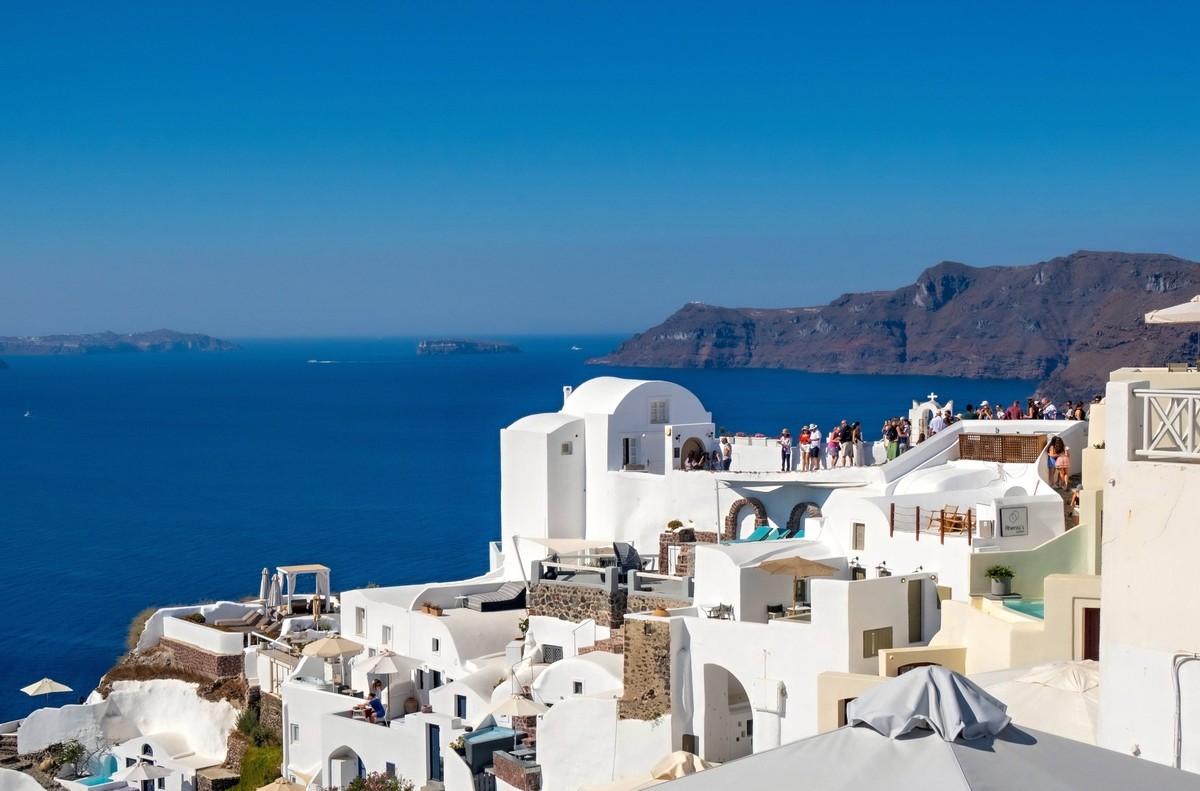 Touristen bewundern die atemberaubende Aussicht auf die Caldera von Santorin in Oia, Griechenland Touristen bewundern die atemberaubende Aussicht auf die Caldera von Santorin in Oia, Griechenland Lice ...