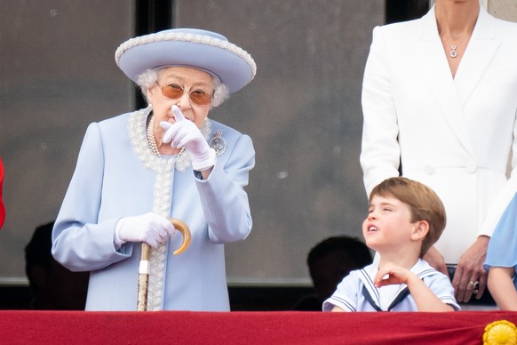 02.06.2022, Gro�britannien, London: K�nigin Elizabeth II. (l) gestikuliert, als sie auf dem Balkon des Buckingham Palastes am ersten Tag der Feierlichkeiten zum Platinjubil�um der Queen mit Prinz Loui ...