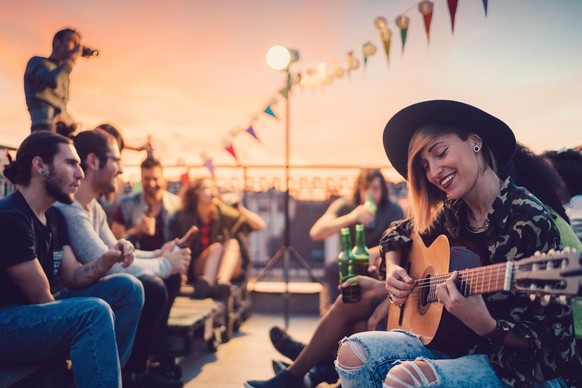 Group of friends enjoying a social gathering with guitar music on the rooftop