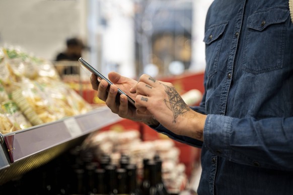 Close-up of mid adult man using smart phone in supermarket model released Symbolfoto property released AFVF07955