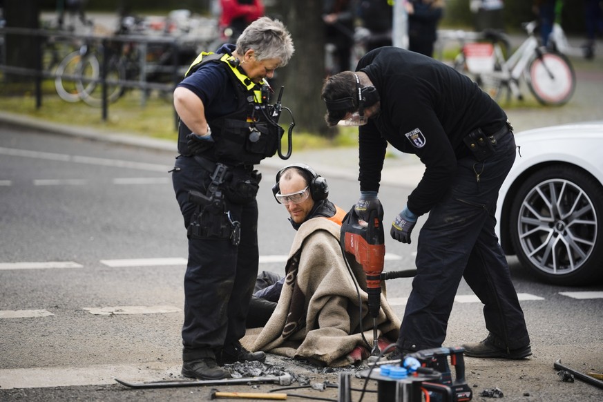 Police removes the pavement next to the hand of an climate activist during a protest against the climate policy of the German government in Berlin, Germany, Monday, April 24, 2023. German climate acti ...