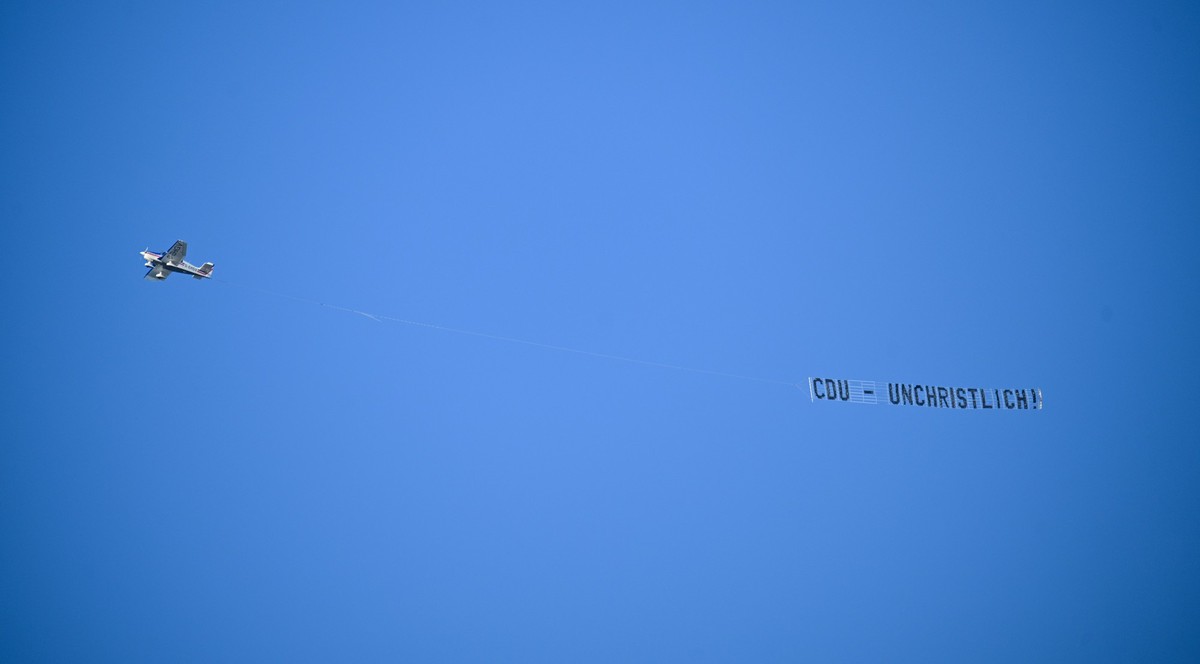 03.02.2025, Berlin: Ein Flugzeug zieht vor Beginn des 37. Bundesparteitags der CDU im CityCube Berlin ein Banner mit der Aufschrift &quot;CDU - unchristlich&quot; hinter sich her. Foto: Sebastian Chri ...