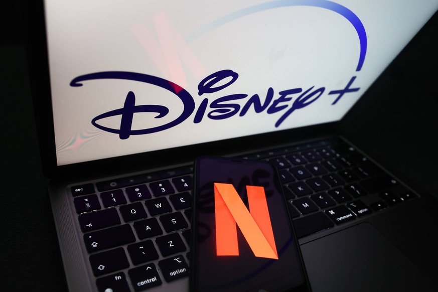 Popular Streaming Services Photo Illustrations Netflix icon displayed on a phone screen and Disney logo displayed on a laptop screen are seen in this illustration photo taken in Krakow, Poland on Nove ...