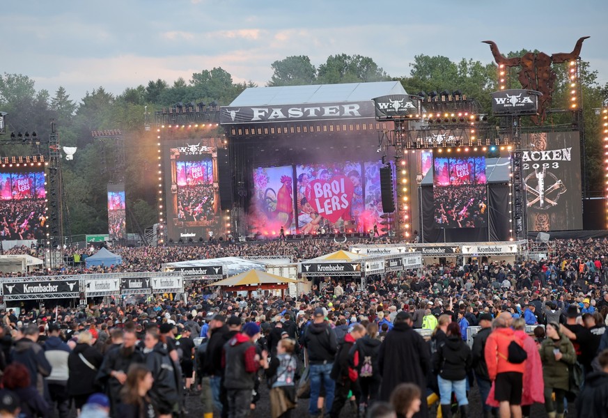 02.08.2023, Schleswig-Holstein, Wacken: Metal-Fans feiern auf dem Festivalgelände vor der «Faster-Stage», einer der beiden Hauptbühnen, bei einem Konzert der Band «Broilers». Das Wacken Open-Air (WOA) ...