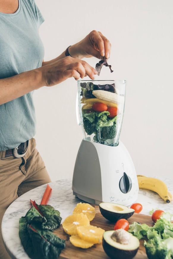 Woman filling fruit and vegetable into blender model released Symbolfoto PUBLICATIONxINxGERxSUIxAUTxHUNxONLY IPF00413