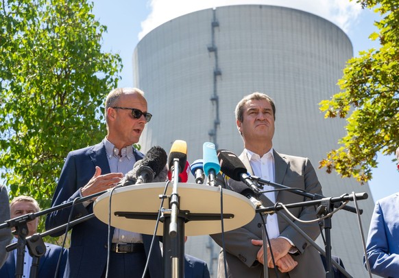 CDU-Bundesvorsitzende Friedrich Merz (l) und Markus Söder, (CSU) Ministerpräsident von Bayern, geben nach ihrem Besuch des Kernkraftwerk Isar 2 (im Hintergrund) eine Pressekonferenz.