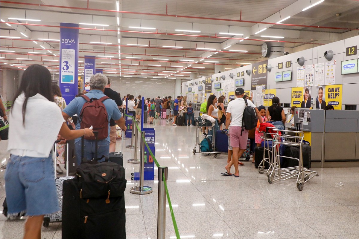 15.08.2025, Spanien, Palma: Fluggäste stehen im Flughafen Palma de Mallorca an einem Schalter der Fluggesellschaft Ryanair. Gewerkschaften wollen mit einem zunächst dreitägigen Streik eine Verbesserun ...