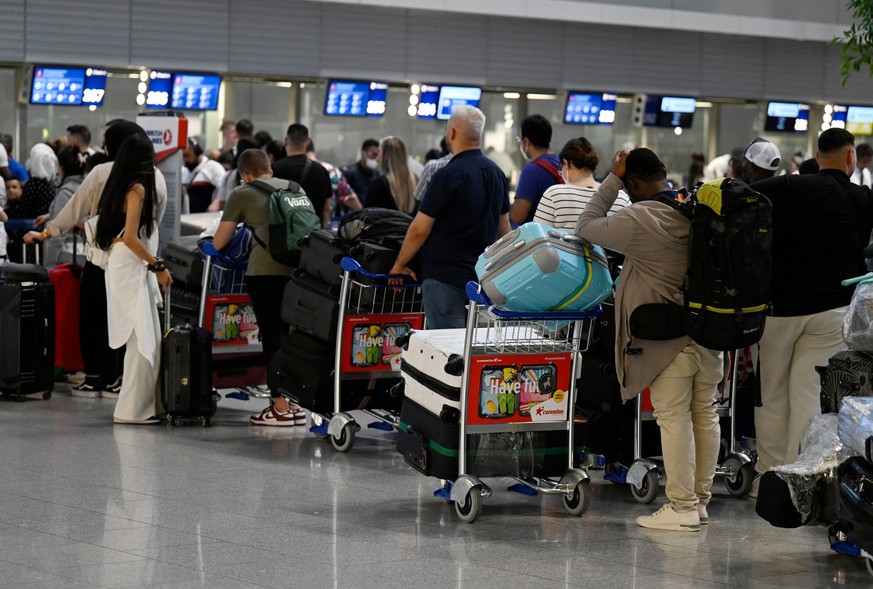 Reisende stehen in Schlangen vor den Check-In-Schaltern im Terminal des Düsseldorfer Flughafens.