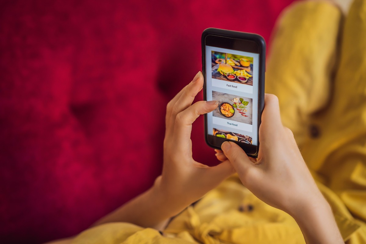 Young woman orders food for lunch online using a smartphone.