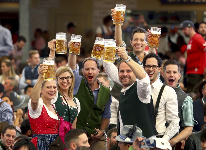 FILE - Visitors lift glasses of beer during the opening of the 186th 'Oktoberfest' beer festival in Munich, Germany, on Sept. 21, 2019. The Oktoberfest is on tap again in Germany after a two-year pand ...