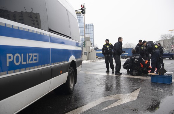 06.02.2023, Berlin: Polizeibeamte versuchen an der Halenseestraße die festgeklebte Hand eines Demonstranten der Umweltschutzgruppe &quot;Letzte Generation&quot; vom Asphalt zu lösen. Nach einer länger ...