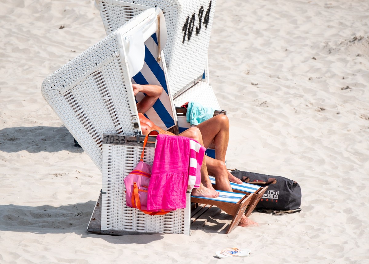 ARCHIV - 21.07.2024, Schleswig-Holstein, Sankt Peter-Ording: Zwei Menschen liegen bei Sonnenschein am Strand an der Nordsee in einem Strandkorb, (zu dpa: