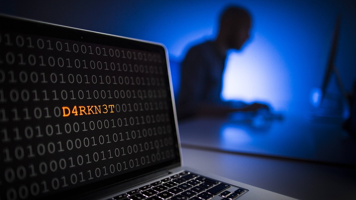 Illustration zum Thema Darknet . Nahaufnahme eines Laptops mit Binaercode. Im Hintergrund sitzt ein Mann an einem Computer, Berlin, 13.01.2017. MODEL RELEASE vorhanden, Model release available, MODEL ...