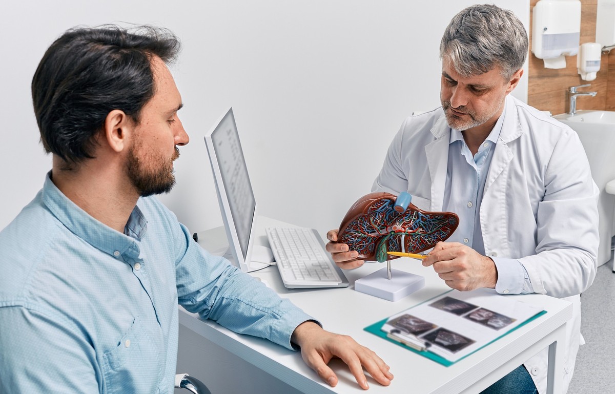Gastroenterologist doctor explaining liver and gallbladder problems using anatomical model to patient during clinic visit. Treatment of gallbladder and liver diseases