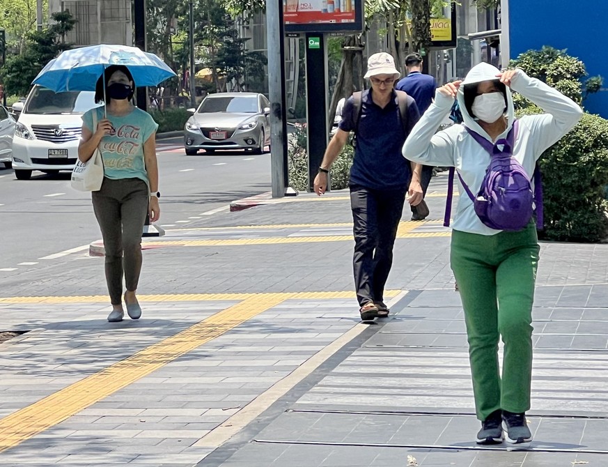 ARCHIV - 01.05.2024, Thailand, Bangkok: Menschen auf der Silom Road in Bangkok versuchen, sich vor der Hitze zu sch