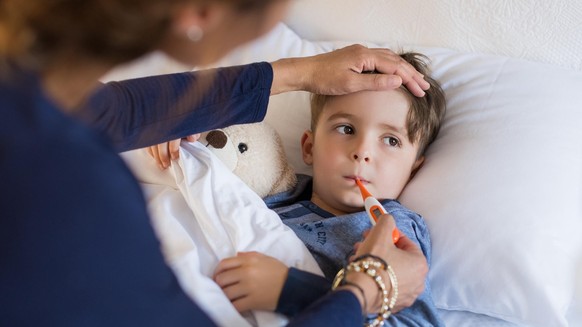 Einem Kind wird Fieber gemessen.