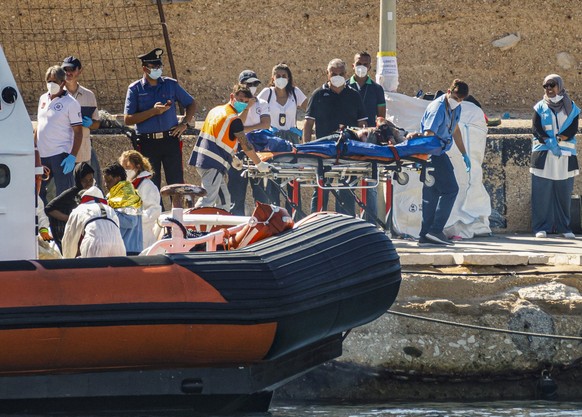 21.10.2022, Italien, Lampedusa: �berlebende werden auf der sizilianischen Insel an Land gebracht. Die italienische K�stenwache hat zwei tote Kinder von einem Boot mit 38 Migranten im zentralen Mittelm ...