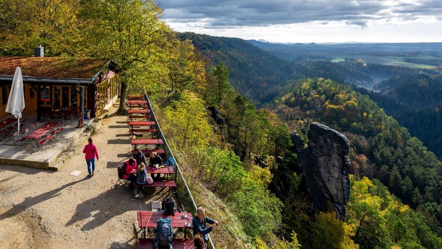 25.10.2022, Deutschland, Sachsen, Sächsische Schweiz, Hohnstein: Touristen schauen bei sonnigem Wetter von der Brandbaude bei Hohnstein aus über die Sächsische Schweiz. *** 25 10 2022, Germany, Saxony ...