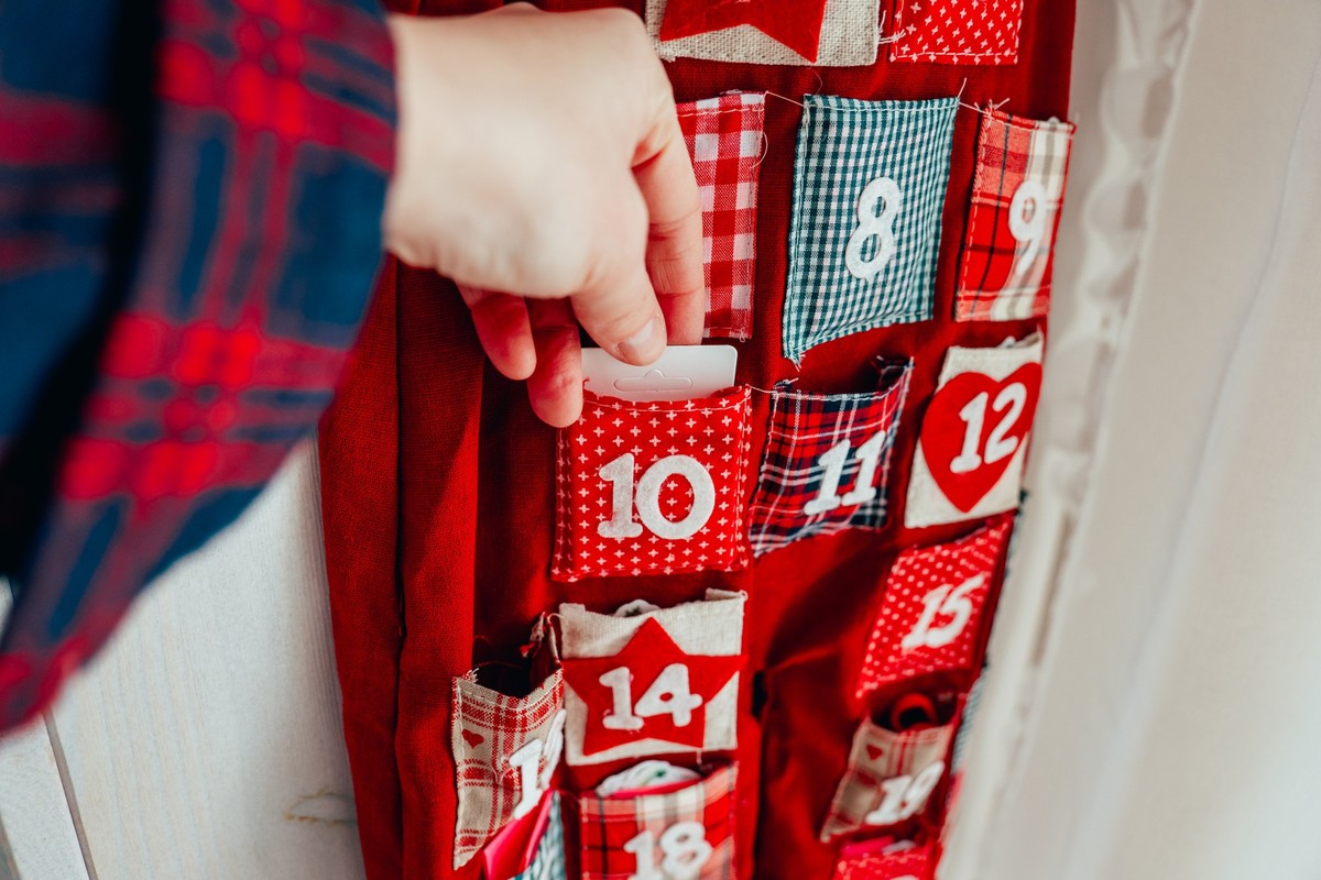 Advent calendar. Preparing for Christmas. The hand puts the gift in the pocket.A hand takes out an advent calendar gift from its pocket