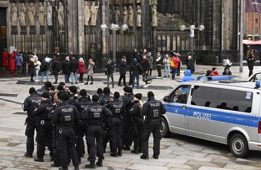 24.12.2023, Nordrhein-Westfalen, Köln: Polizisten patrouillieren am Eingang des Kölner Doms am Weihnachtstag. Aufgrund von Hinweisen auf einen geplanten islamistischen Anschlag hat die Polizei die Sic ...