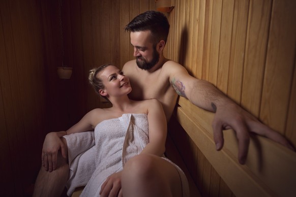 Young couple enjoying the sauna session together and relaxing