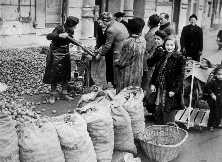 1945: Women in Berlin buying potatoes from a heap in the middle of a street. This was the staple food during the winter. (Photo by Keystone/Getty Images)