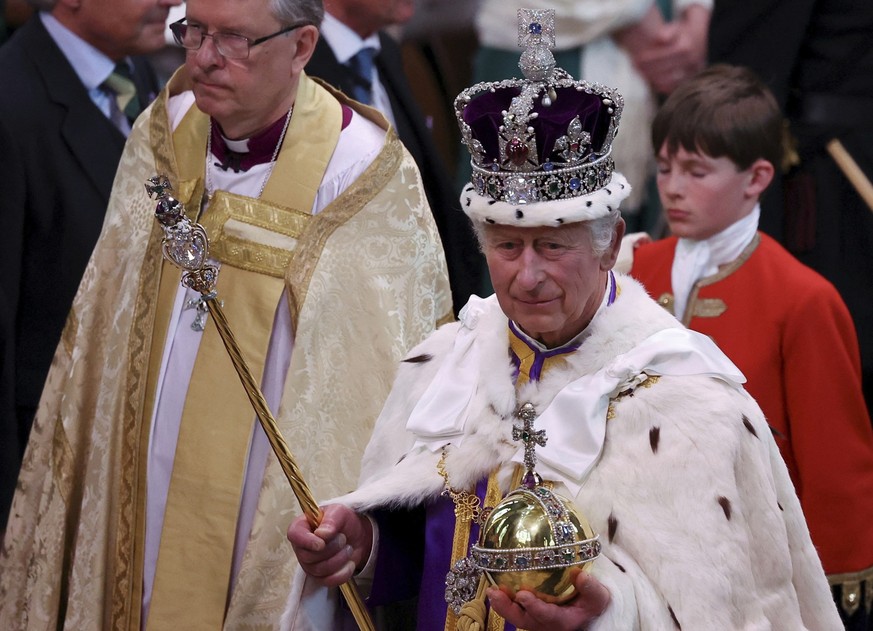 06.05.2023, Großbritannien, London: Großbritanniens König Charles III. verlässt nach der Krönungszeremonie mit der Imperial State Crown, einem Zepter und dem Reichsapfel die Westminster Abbey. Zur Krö ...