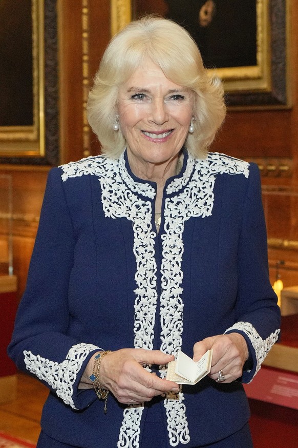Britain&#039;s Queen Camilla holds a miniature book she received during a reception at Windsor Castle for authors, illustrators and binders who have been involved in the new Miniature Library collecti ...