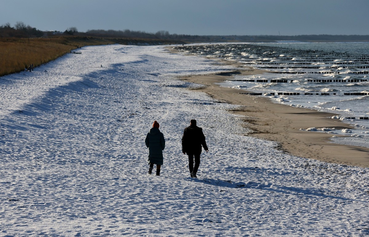 13.12.2022, Mecklenburg-Vorpommern, Wustrow: Spaziergänger sind am schneebedeckten Ostseestrand unterwegs. Tagelanger Frost sorgt für winterliche Impressionen im Norden. Foto: Bernd Wüstneck/dpa +++ d ...