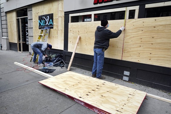 Workers hangs sheets of plywood on storefronts, on New York&#039;s Upper West Side, Tuesday, Nov. 3, 2020. Retailers are boarding up their windows or add extra security personnel in some of their loca ...