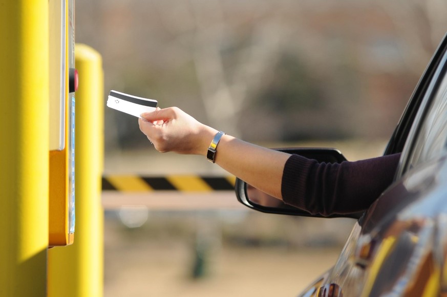 a hand reaching out to insert parking voucher for parking payment