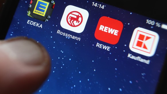 ILLUSTRATION - 02.12.2022, Bayern, Kaufbeuren: Icons der Apps von den Handelsketten Edeka (l-r), Rossmann, REWE und Kaufland sind auf dem Display eines iPhones zu sehen. Wer angesichts der Inflation b ...