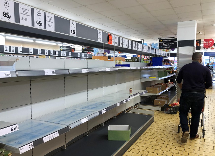 WALLINGTON, ENGLAND - MARCH 18: (EDITORS NOTE: This image were shot on an iphone) A shopper walks past empty shelves in a Lidl store on March 18, 2020 in Wallington, United Kingdom. After spates of &q ...