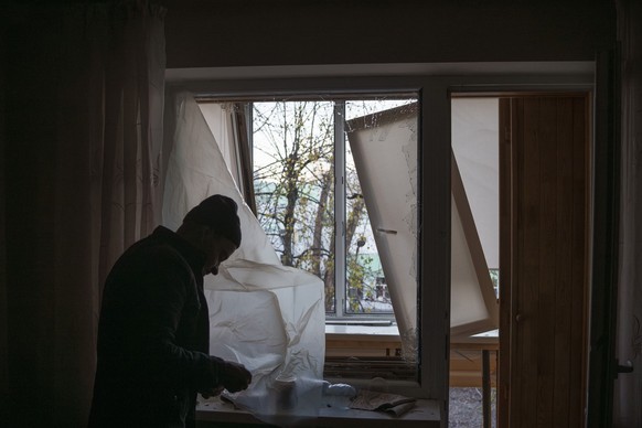 25.11.2023, Ukraine, Kiew: Ein Mann deckt ein zerbrochenes Fenster in seiner Wohnung nach einem russischen Drohnenangriff mit Plastik ab. Russland hat Kiew in der Nacht zu Samstag nach ukrainischen An ...