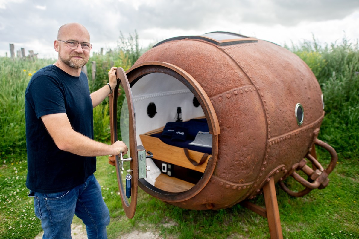 PRODUKTION - 28.06.2024, Niedersachsen, Harlesiel: Andreas Smidt, Betreiber von &quot;Humble Homes&quot; in Harlesiel, steht neben einer ehemaligen Ankerboje in den D