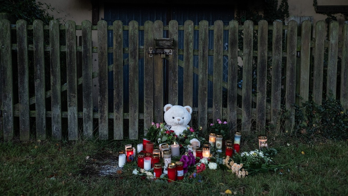 ARCHIV - 30.09.2023, Hessen, Bad Emstal: Kerzen, Blumen und ein großer Plüschteddy sind vor einem Zaun am Fundort zu sehen, wo die Leiche einer vermissten 14-Jährigen aus Nordhessen in einem Waldstück ...