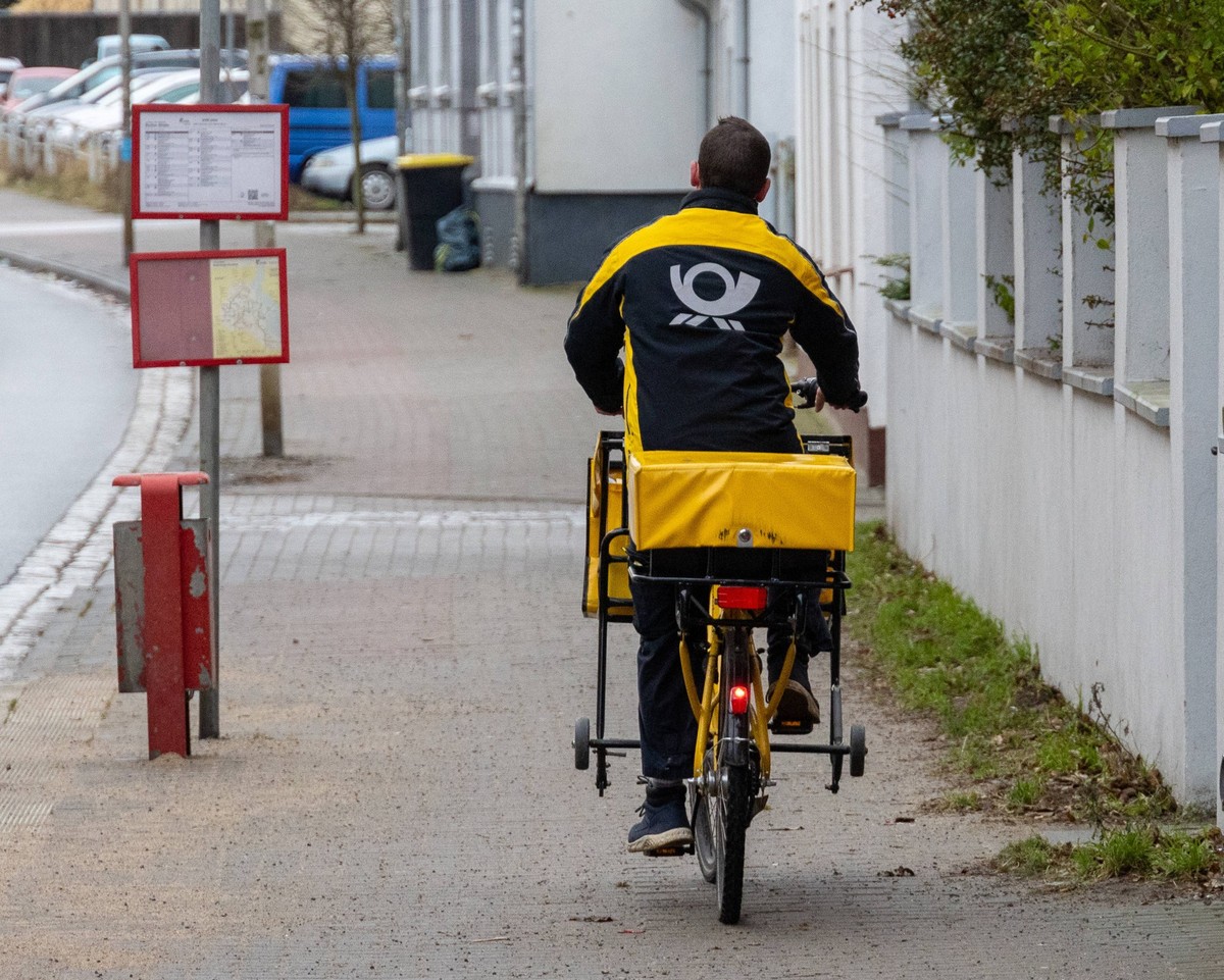 Brieftraeger der Deutschen Post Ein Zusteller der Deutschen Post transportiert Briefe, Zeitungen und Pakete auf dem Fahrrad in Stralsund Landkreis Vorpommern-Ruegen. Stralsund Mecklenburg-Vorpommern D ...
